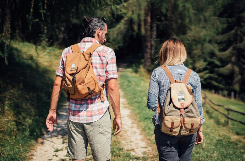 Two hikers with backpacks walking on a path in a lush, forested area. | © Urlaub am Bauernhof Steiermark / Daniel Gollner 
